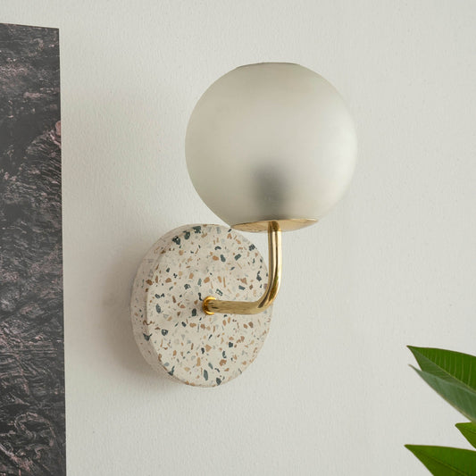 Eros White Wall Lamp with Terrazzo base, Gold-finished Mild Steel, and Frosted Glass shade.  This lamp is available online in India.