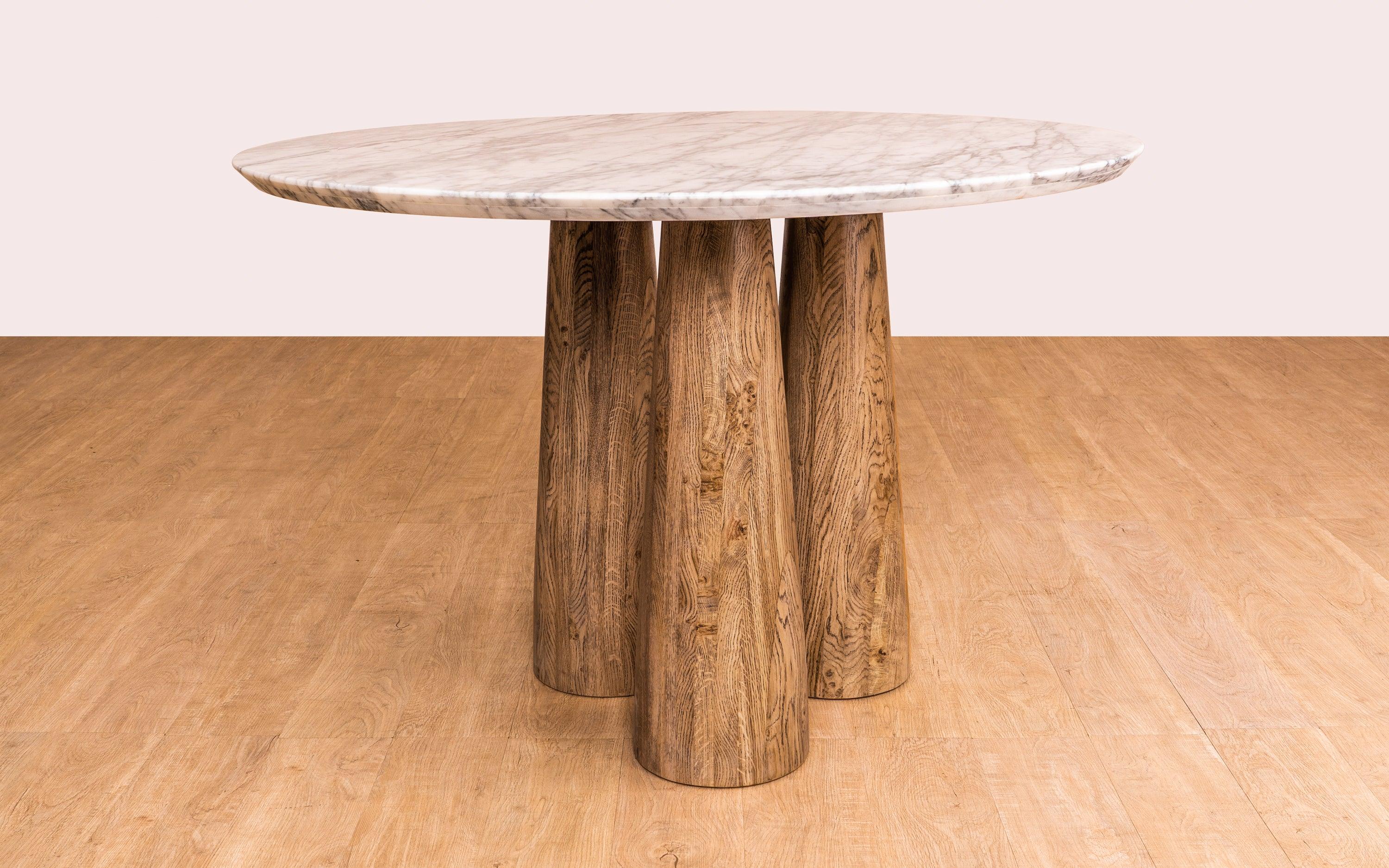 Hump Round Dining Table with Carrara Marble Top and Oak Wood Legs in light brown cerused finish. Luxury marble top dining table for elegant dining rooms.